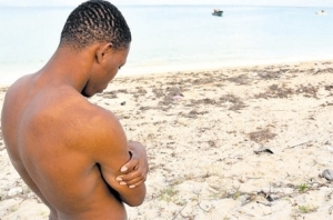 Kenton Williams stands on the beach near the spot where his sister drowned