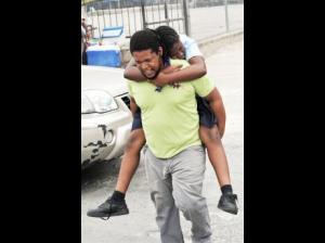 A parent rushes his child who was overcome by smoke to a medical facility. (Photo: Norman Grindley/Gleaner) 